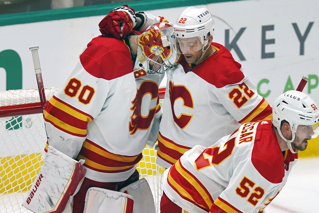 Media by Associated Press - Calgary Flames goaltender Dan Vladar (80) is hugged by teammate Trevor Lewis (22) as MacKenzie Weegar (52) skates away after an NHL hockey game against the Dallas Stars in Dallas, Saturday, Jan. 14, 2023. The Flames won 6-5. (AP Photo/LM Otero)